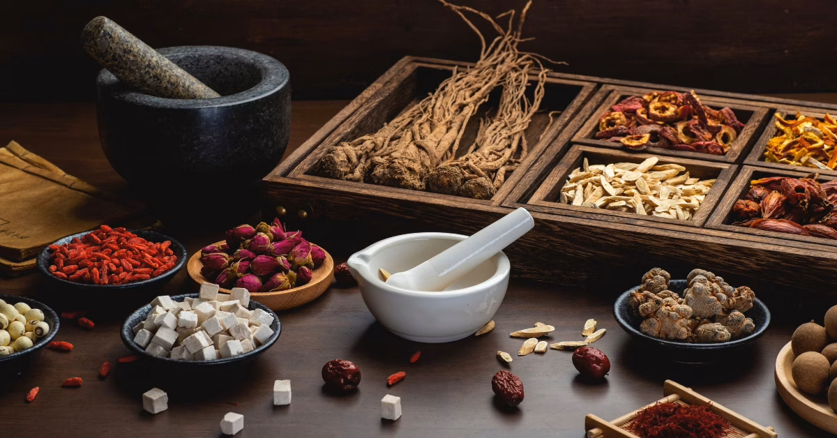 Mesa com várias ervas chinesas, incluindo raízes e flores, utilizadas na medicina tradicional.