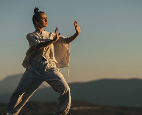 Pessoa praticando Tai Chi ao ar livre, ilustrando práticas da medicina chinesa para equilíbrio energético e bem-estar integral.